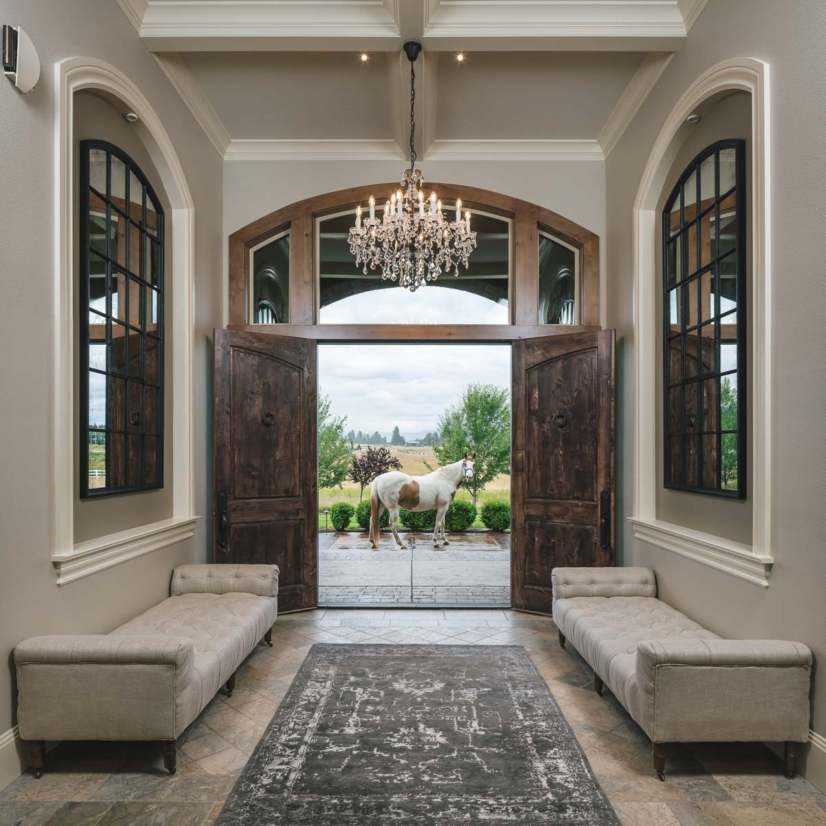 entryway of a grand ranch house with wood doors, runway carpet, and a horse